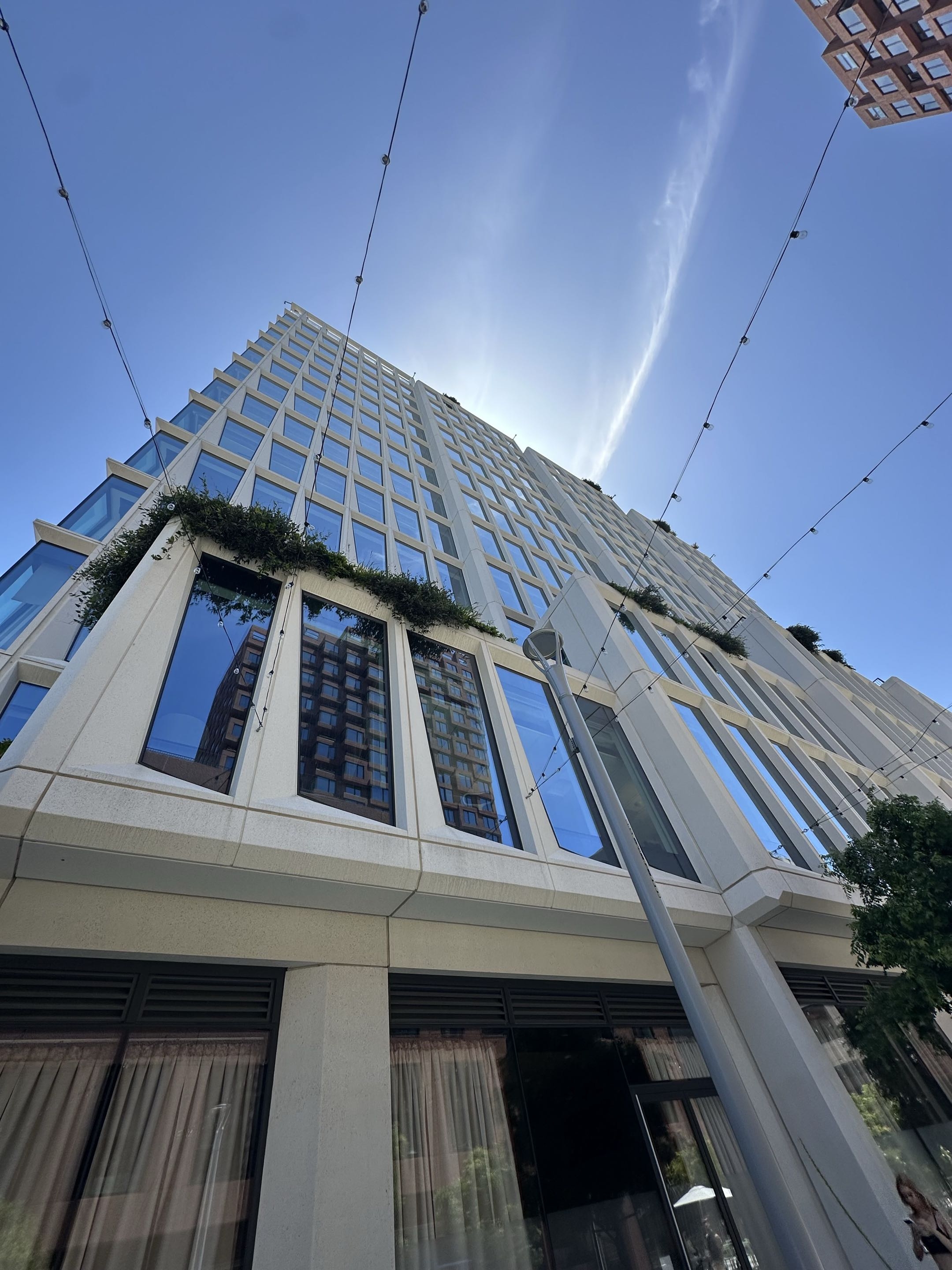 Photo of a white apartment tower with non-rectangular windows, as seen from its base.